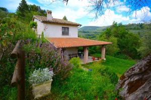 una pequeña casa en una colina con flores delante en VILLA NOCRI - Piscina & Sauna esclusiva, en Montefranco