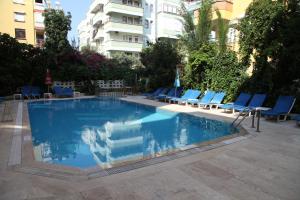 a swimming pool with blue lounge chairs and a building at Alin Hotel in Alanya