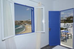 una stanza con una porta blu e vista sulla spiaggia di MARKOS BEACH rooms & studios a Mykonos Città