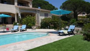una piscina con sillas y sombrillas junto a una casa en Grand Appartement dans Maison avec Piscine Privée, en Fréjus
