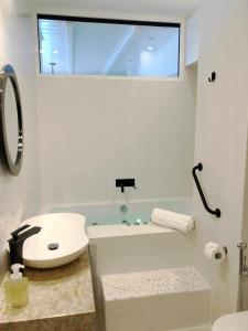 y baño blanco con lavabo y bañera. en Colours Seaview Apartment en Néa Artáki