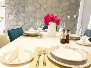 a table with plates and a vase with pink flowers at Colours Seaview Apartment in Nea Artaki