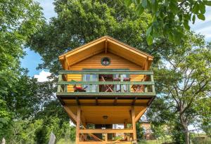 a tree house with a balcony in the trees at Dióliget - Zöld Fészek Lombház in Lovasberény