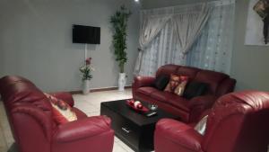 a living room with two red chairs and a table at TINTECH BED & BREAKFAST in Francistown