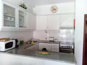 a white kitchen with white cabinets and a microwave at Casa de Praia da Lú in Figueira da Foz