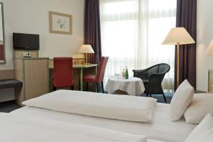ein Hotelzimmer mit einem Bett und einem Tisch und Stühlen in der Unterkunft Apart' Hotel in Kehl am Rhein