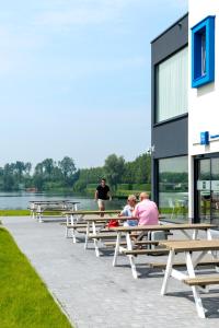 personas sentadas en mesas de picnic frente a un edificio en ibis budget Brugge Jabbeke, en Jabbeke