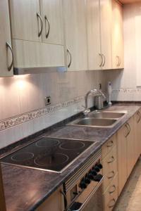 a kitchen with a stove and two sinks and cabinets at PISO EXTERIOR COMPLETO A 20 ' DE BARCELONA. in Sabadell