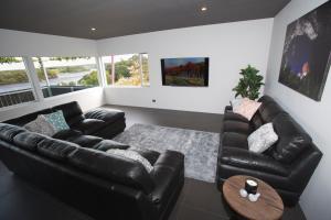 a living room with black leather furniture and a table at Nelson Victoria Luxury Holiday Accommodation in Nelson