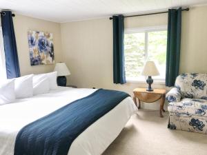 a bedroom with a bed and a chair and a window at Churchill Pointe Inn in Hubbard Lake