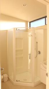 ein weißes Bad mit einer Dusche und einem WC in der Unterkunft Sunset Motel in Fox Glacier