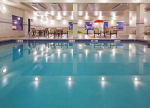 uma piscina num hotel com cadeiras e mesas em Holiday Inn Express & Suites Sioux Falls Southwest, an IHG Hotel em Sioux Falls