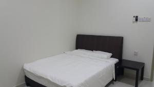 a bedroom with a white bed and a black chair at My STW Home 2 in Sitiawan