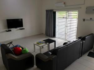 a living room with couches and a table and a tv at My STW Home 2 in Sitiawan