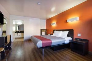 a hotel room with a bed with an orange wall at Motel 6-Claremont, CA in Claremont +27 photos