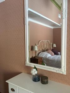 a mirror on a wall with a bed in a room at Cafe-Restaurant & Hotel Saima in Savonlinna