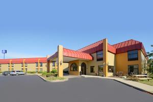 Days Inn & Suites by Wyndham Kalamazoo في كالامازو: مبنى كبير وامامه موقف سيارات