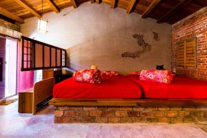 a bedroom with a bed with red sheets and pillows at Lungta BnB in Jiufen