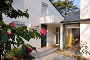 a white house with a red rose in front of it at Contact Hôtel du Parc in Orvault