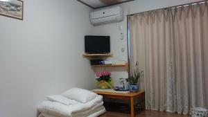 ein Wohnzimmer mit Sofa und Fernseher in der Unterkunft Furusatono Ie in Kyoto