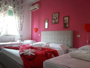 - une chambre avec 3 lits et un mur rose dans l'établissement Hotel Fiammetta, à Rimini