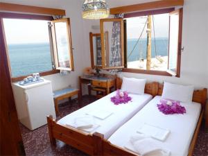 a bedroom with two beds with a view of the ocean at Pension Mylos in Agios Nikolaos