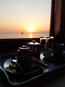 a table with two tea pots and spoons on it with the sunset at Pension Mylos in Agios Nikolaos