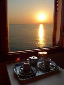 a table with two tea sets and a view of the ocean at Pension Mylos in Agios Nikolaos