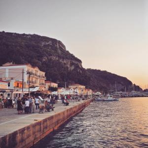 a group of people sitting on a pier next to the water at Samaina Port Hotel in Karlovasi