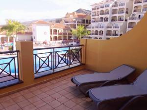 balkon z krzesłami i widokiem na basen w obiekcie Apartamentos Dinastia w mieście Los Cristianos