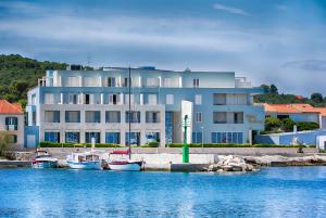 a large white building with boats in the water at Hotel Pastura in Postira