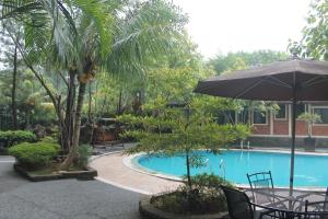 an umbrella and chairs next to a swimming pool at New Green Sentul Resort in Bogor
