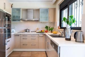 a kitchen with white cabinets and a large window at Villa Ismini in Kato Daratso