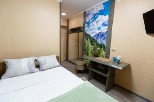 una camera con letto e scrivania con un dipinto sul muro di Hotel Shumak a Ulan-Ude