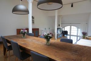 a large wooden table with chairs and flowers on it at Alter Konsumverein App N°9 in Westerland