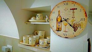 un orologio su una mensola con tazze e una bottiglia di vino di Trullo Sereno Angelo a Locorotondo
