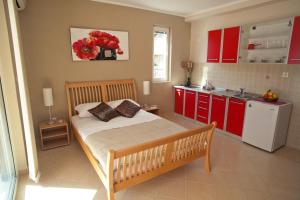 a bedroom with a bed and a kitchen with red cabinets at Apartments Bella Vista in Kamenari