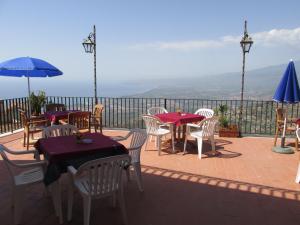 taras ze stołami, krzesłami i parasolem w obiekcie Hotel Panorama di Sicilia w mieście Castelmola