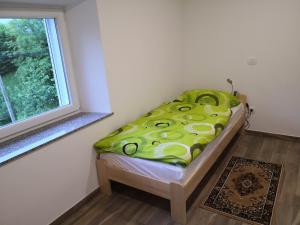 a small bed in a room with a window at Apartmaji Zupan in Bohinjska Bela