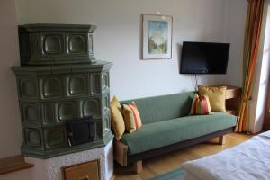 a living room with a green couch and a tv at Haus Klaushofer in Fuschl am See