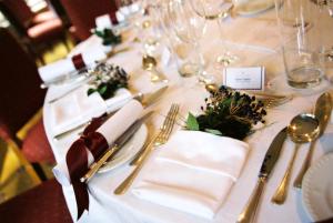un tavolo con tovaglioli bianchi e argenteria di Roman Camp Country House Hotel a Callander