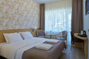 a hotel room with a bed and a desk and a window at Amber Sea Hotel & Spa in Jūrmala