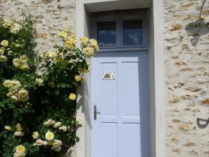 a white door in a stone building with flowers at L'Etable d'Orgerus in Orgerus