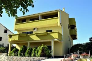 a yellow building with bushes in front of it at Apartmani Erna in Pašman