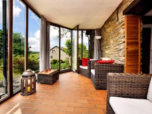 um alpendre com cadeiras e janelas em Romantic holiday house in the Ardennes with garden and view em Nadrin