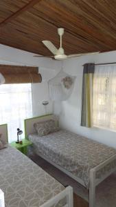 a bedroom with two beds and a ceiling fan at Le Paradiso Apartments in Rodrigues Island