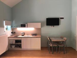 a kitchen with a table and a small kitchen with a television at White Crow House in Hévíz