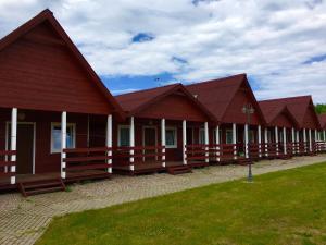 a row of wooden buildings with grass in front at Rodzinna Kraina in Ustka