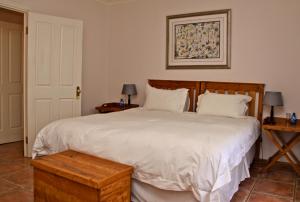 1 dormitorio con 1 cama blanca grande y 2 mesas en Red Mountain House en Clarens