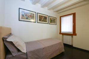 威尼斯的住宿－Ca' Fenice 1921，卧室配有一张床,墙上有三幅照片